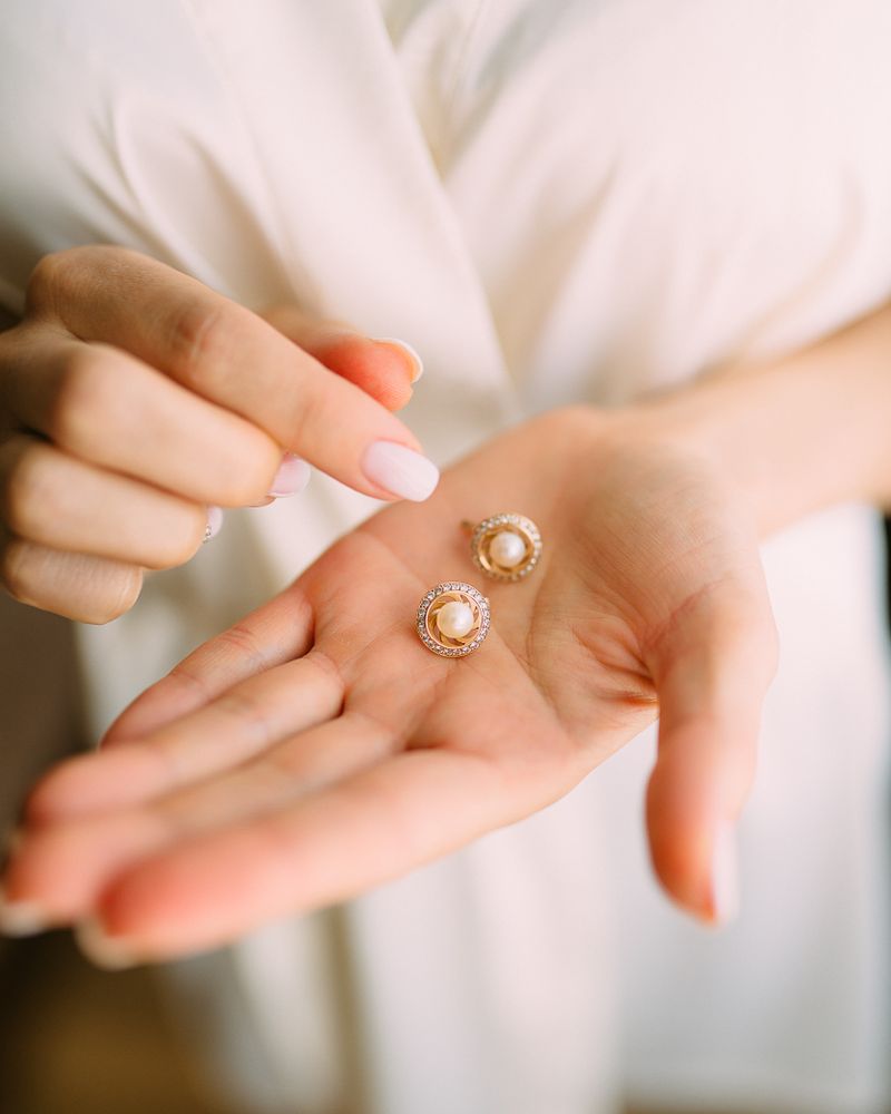 Pearl and gold earrings held in the hand